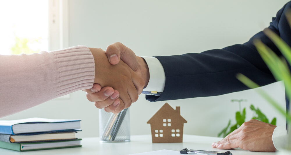 Couple shaking hands with solicitor after signing a document.