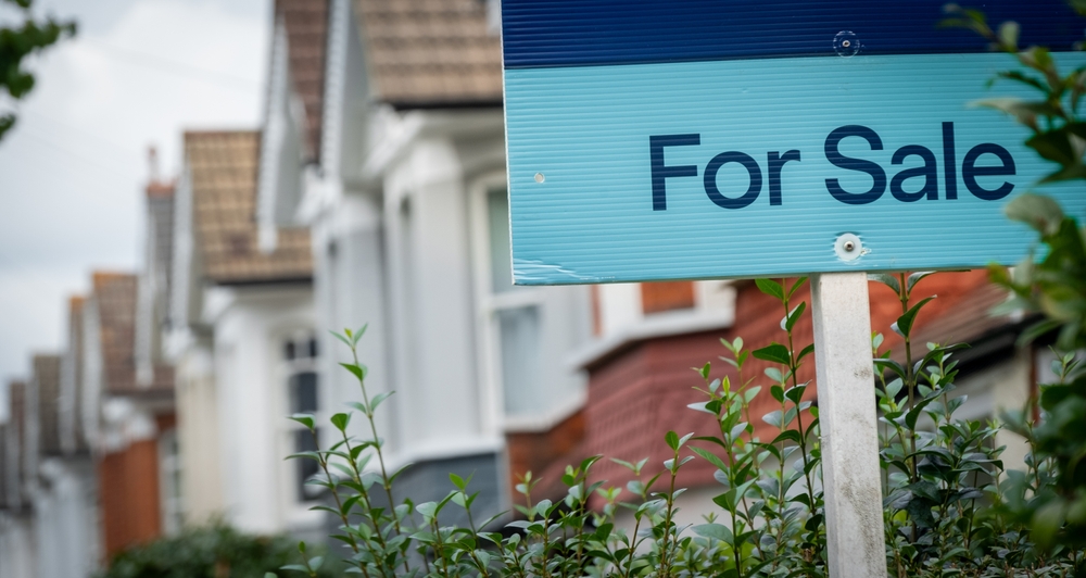 A for sale sign outside of a row of houses.